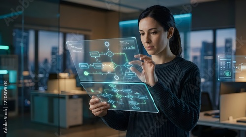 Woman using transparent tablet with digital flowchart in modern office