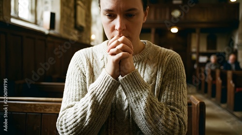 Person praying in church pew with hands clasped during religious service