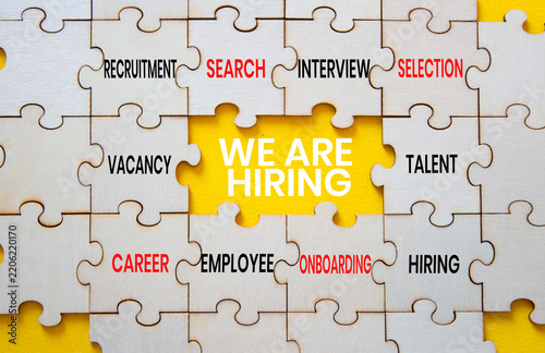 We are hiring symbol. Concept words we are hiring on wooden puzzle pieces. Beautiful yellow background. Recruitment concept. Copy space.