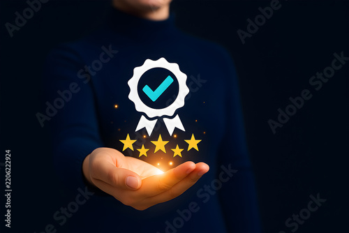 Hand holding glowing quality assurance ribbon badge with checkmark and five stars for business excellence certification concept