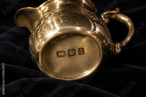 Antique silver cream jug with hallmark stamps on dark velvet, craftsmanship and heritage concept