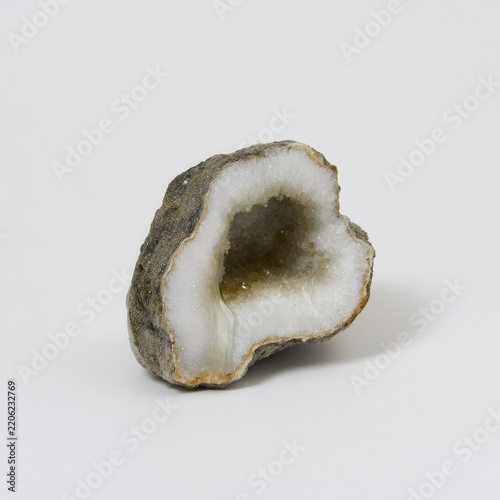 A geode with a white crystalline interior is showcased against a neutral background