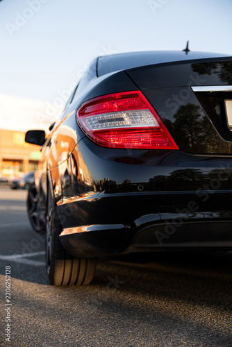 Black car parked in a lot near a building during sunset