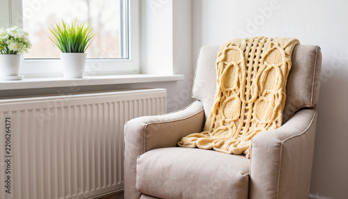 Cozy armchair with knitted throw by window, warmth and comfort