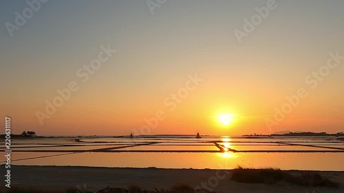 Golden sunset over tranquil salt pans near Trapani, Italy