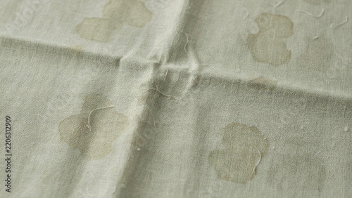 Stained beige fabric with watermarks and loose threads close up shot