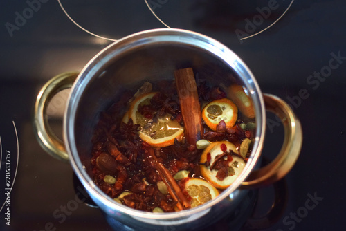 Obraz na płótnie Sliced oranges, spices, and cinnamon simmer in a pot for mulled wine preparation