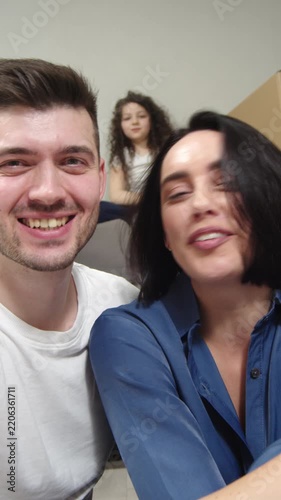 Happy family gathering for playful selfie video as smiling adults and child move together toward camera in bright home interior, celebrating joyful family connection