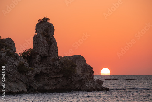 Sunset over dramatic coastal cliffs and rugged rock formations at golden hour. An ethereal view of nature's power.
