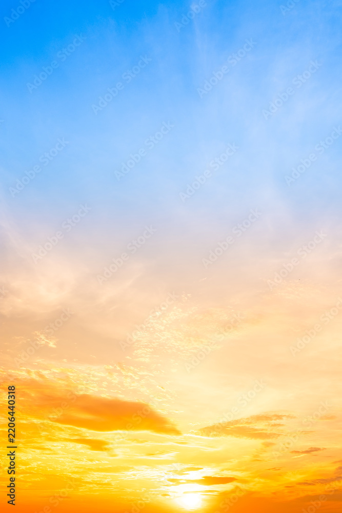 Fototapeta premium Sky sunset,Beautiful sunrise sky with vibrant gradient orange and gold colors and soft blue, Clear atmosphere with wispy clouds. Peaceful, perfect for background and copy space, vertical