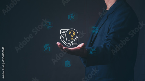 Corporate businessman holding virtual hologram of phone with question mark and customer service for digital helpdesk support, smart CRM strategy, and online contact communication concept.