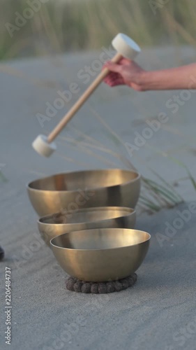 Hand playing singing bowls on a sandy beach at sunset
