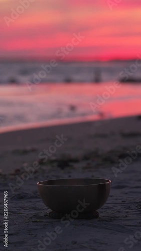 Singing bowl on beach at sunset with hand and mallet