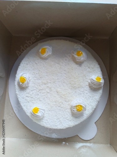 white frosted cake with yellow flower decorations in box