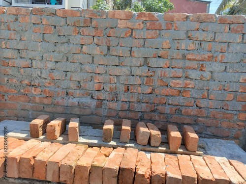 stacked clay bricks beside unfinished brick wall
