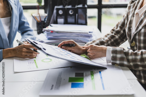 Businesswoman engaging in a discussion about financial data, analyzing charts and graphs on a clipboard during a productive office meeting focused on strategy and growth.