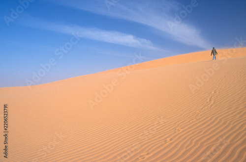 Single person walking in the Sahara Desert, concept of leaving and solitude, scanned from transparency 1989