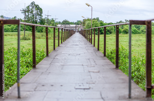 Boon Soong Iron Bridge Walkway in Takua Pa, Phang Nga, Thailand. Long pedestrian walkway of Boon Soong Iron Bridge, surrounded by tropical greenery, with symmetrical railings and strong leading lines.