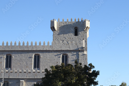 Historic stone castle with a tall fortified tower and crenellated walls, photographed under a clear blue sky as part of a medieval fair and European heritage setting, with distinctive stonework.