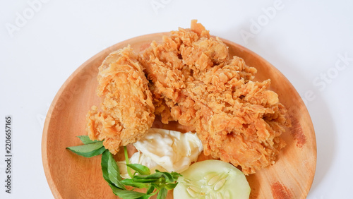 Crispy Golden Fried Chicken Served on a Wooden Plate with Sliced Cucumber and Cabbage, Delicious Breaded Poultry Snack Isolated on White Background