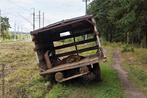 Bild auf Leinwand Old rustic wooden cart abandoned on a rural dirt path near a railway track, feat