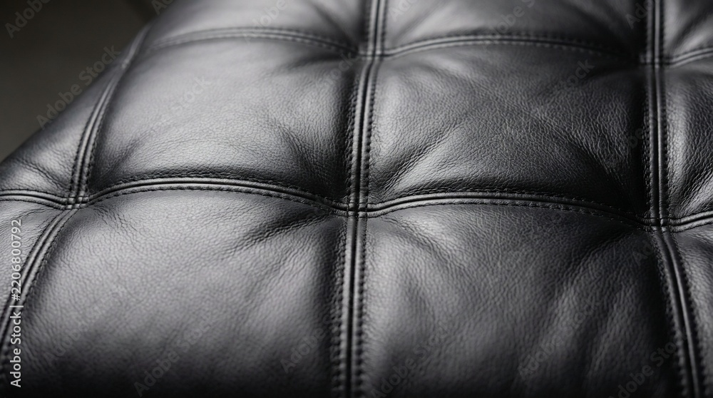 Fototapeta premium Macro shot of high quality black synthetic leather material featuring elegant tufted design and detailed decorative stitching.