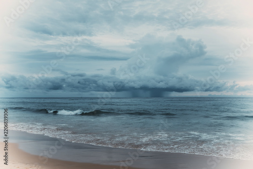 Dramatic storm clouds and rain over the sea with ocean waves on a moody overcast day