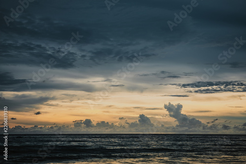 Dramatic sunset over the sea with heavy dark clouds and golden light on the horizon