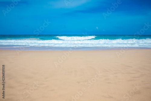 Tropical paradise beach with golden sand and turquoise ocean waves under blue sky, summer holiday background