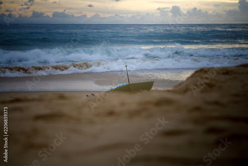 Lost umbrella on the sand with powerful ocean waves at sunset, conceptual beach landscape