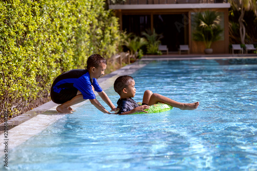 Young Asian Brothers Enjoying Swimming Pool Activities on a Sunny Day