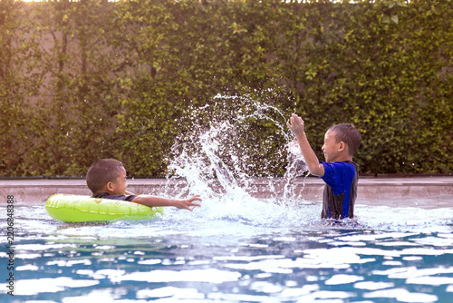 Excited Boy Splashing Water in Swimming Pool During Summer Vacation