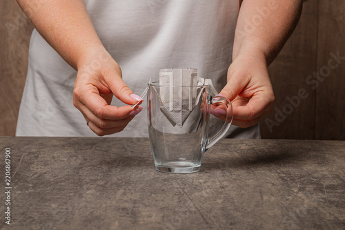 Installing drip coffee bag on glass mug