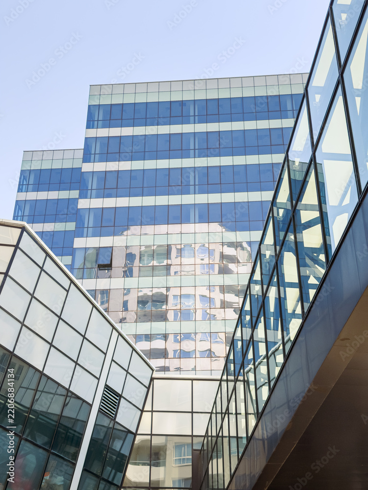 Obraz premium Building reflections in a modern urban setting with glass architecture and clear sky