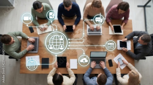 Team of business professionals working at table with global network interface and communication icons illustrating collaborative project management and remote team connectivity solutions