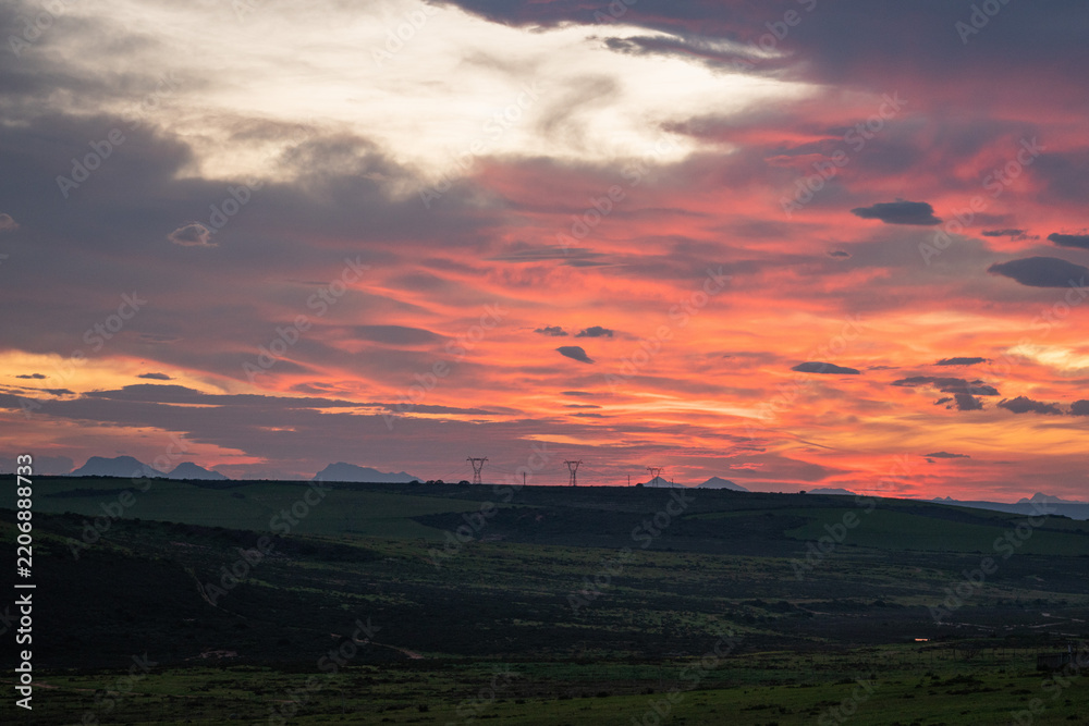 Fototapeta premium Vibrant clouds painting sky during sunset over landscape