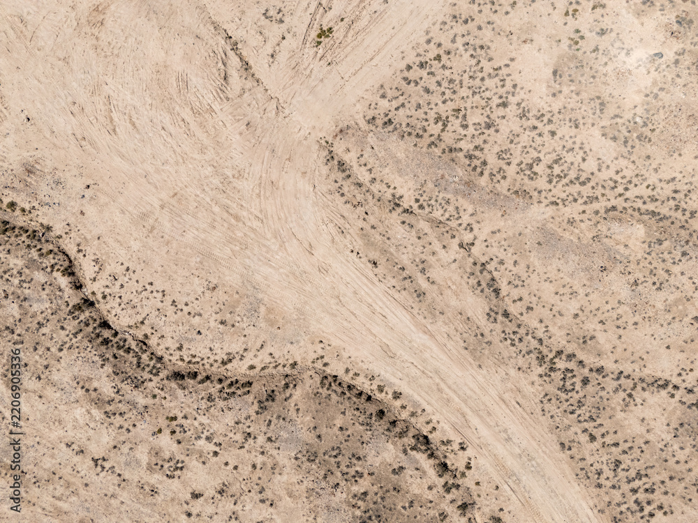 Obraz premium aerial view of winding dirt road through desert shrubs