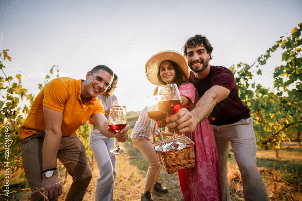 Obraz premium Group of friends reaching out with wine glasses for a toast in vineyard