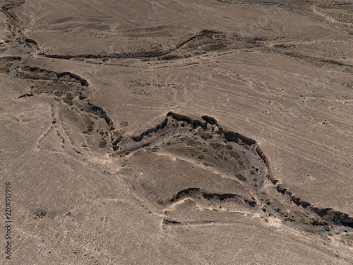 Aerial view of eroded gullies and dry cracked earth in barren desert landscape