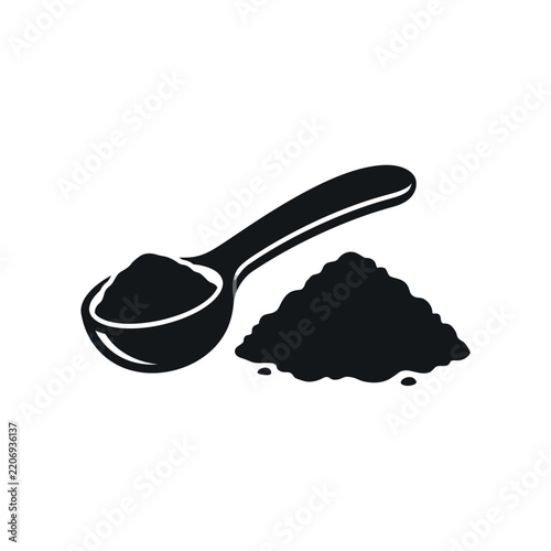 Spoonful of dark powder next to a small pile of the same powder.