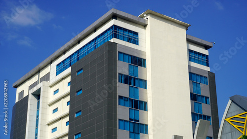 Wide low-angle shot of a multi-story commercial building corner, showcasing full height and rooftop structures.