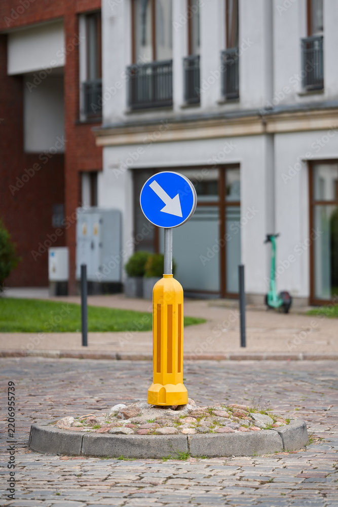 Fototapeta premium Richtungspfeil als Verkehrszeichen an einem Kreisverkehr in der Innenstadt von Danzig, Gdansk in Polen