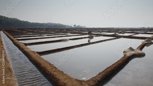 Salt Farming A Dedicated Worker Responsibly Tending to Expansive Salt Pans Under a Clear, Blue Sky in India
