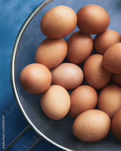 Top view of fresh brown chicken eggs in a stainless steel wire mesh strainer. Healthy organic food, poultry farm product and cooking ingredient.