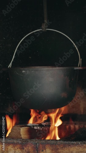 Cooking in a cauldron over an open fire, outdoor cooking, rustic food preparation.
