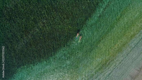 Top-down aerial view of a couple swimming and snorkeling in the clear, shallow waters of the Pacific Ocean near the shore of Coiba National Park, Panama during a sunny summer day - stock video