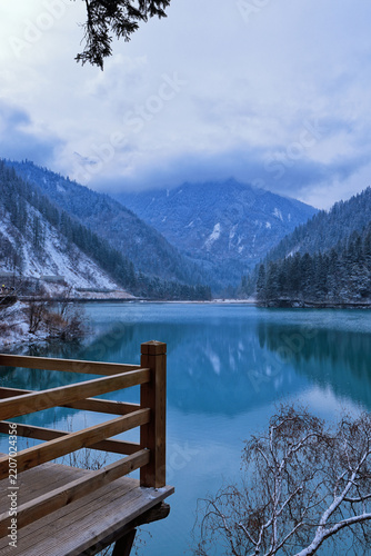 Fotografie Wooden viewing platform overlooking turquoise lake and snow-covered mountains in
