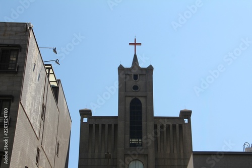 Obraz na plátně Modern concrete church tower with a holy cross symbol under bright sunlight