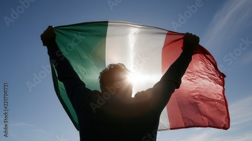 Person holds Italian flag against the sun in a clear sky during a daytime event