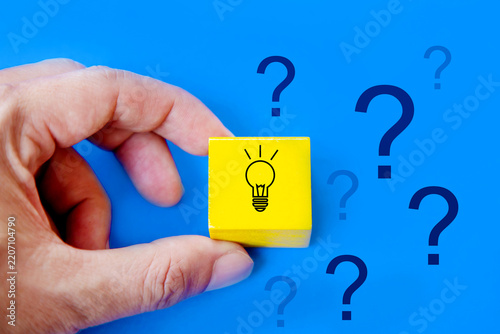 Hand holding light bulb among question marks; Solution and Problem solving Concept